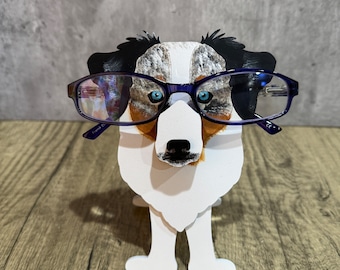 May include: A blue and white dog figurine with blue glasses, standing on a wooden surface.