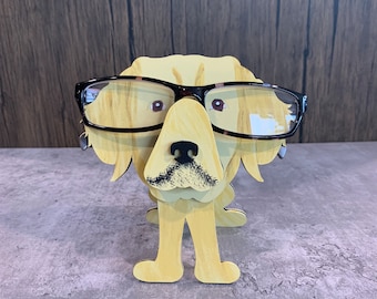 May include: A wooden golden retriever dog figurine wearing black framed glasses. The figurine is standing on a grey surface.