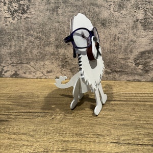 May include: White wooden lion figurine wearing blue glasses. The lion is standing on a wooden surface.