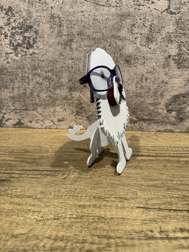 May include: White wooden lion figurine wearing blue glasses. The lion is standing on a wooden surface.