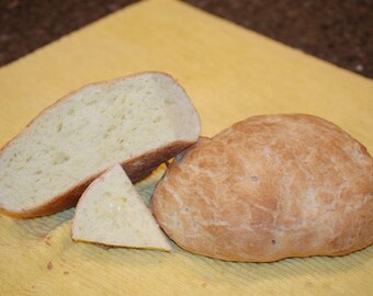 May include: Three slices of freshly baked bread on a yellow tablecloth. The bread is light brown and has a soft, fluffy texture.