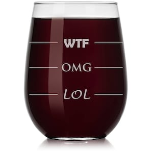 May include: A clear glass wine glass with a red wine inside. The glass has the words "WTF", "OMG", and "LOL" etched on it.