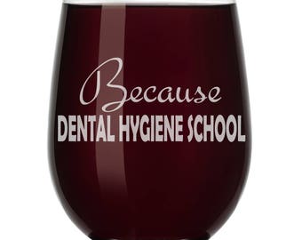 May include: A clear glass wine glass with a red wine inside. The glass has the text "Because Dental Hygiene School" etched on the front.