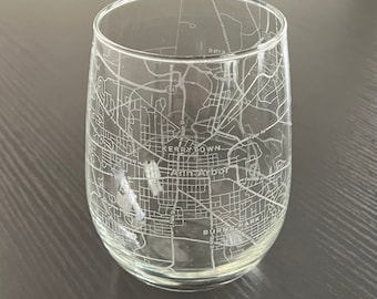 May include: A clear glass wine glass with an etched design of the city of Ann Arbor, Michigan. The design includes the names of neighborhoods like Kerrytown and Burns Park.