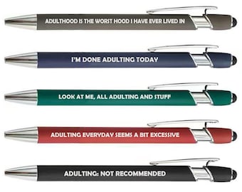 May include: A set of five retractable ballpoint pens in gray, navy, teal, red, and black. Each pen features a silver clip, a stylus tip, and white text: ADULTHOOD IS THE WORST HOOD I HAVE EVER LIVED IN, I'M DONE ADULTING TODAY, LOOK AT ME, ALL ADULTING AND STUFF, ADULTING EVERYDAY SEEMS A BIT EXCESSIVE, and ADULTING: NOT RECOMMENDED.