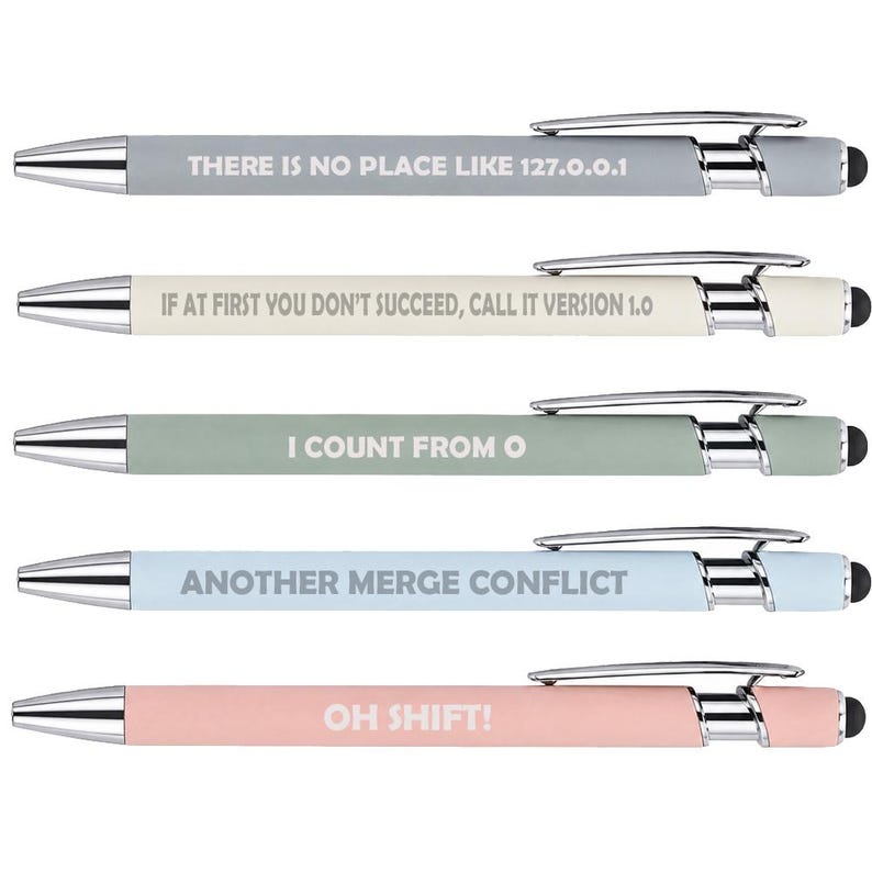 May include: Five retractable ballpoint pens with chrome accents and black stylus tips. Each pen features a unique matte barrel color and white text: THERE IS NO PLACE LIKE 127.0.0.1, IF AT FIRST YOU DON'T SUCCEED, CALL IT VERSION 1.0, I COUNT FROM 0, ANOTHER MERGE CONFLICT, and OH SHIFT!