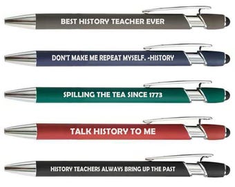 May include: A set of five retractable ballpoint pens in gray, navy, teal, red, and black. Each pen features a silver clip, a stylus tip, and white text: BEST HISTORY TEACHER EVER, DON'T MAKE ME REPEAT MYSELF. -HISTORY, SPILLING THE TEA SINCE 1773, TALK HISTORY TO ME, and HISTORY TEACHERS ALWAYS BRING UP THE PAST.