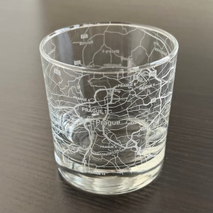 May include: A clear glass tumbler with an etched map of Prague, Czech Republic. The map includes the city's districts, including Prague 1, Prague 4, Prague 6, Prague 8, and Prague 9.