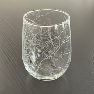 May include: A clear glass wine glass with a laser-etched design of the city of Athens, Georgia. The design includes street names and highway numbers. The text "Athens" is visible in the center of the design.