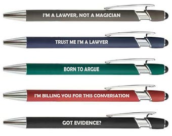 May include: Five ballpoint pens with silver detailing and black touch tips. Each pen features a different coloured barrel and a humorous phrase, such as "TRUST ME I'M A LAWYER" and "BORN TO ARGUE".