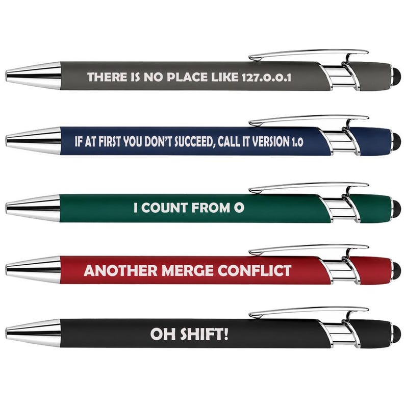 May include: Five retractable ballpoint pens with silver-tone clips and stylus tips. The pens are gray, blue, green, red, and black, each featuring white text: THERE IS NO PLACE LIKE 127.0.0.1, IF AT FIRST YOU DON'T SUCCEED, CALL IT VERSION 1.0, I COUNT FROM 0, ANOTHER MERGE CONFLICT, and OH SHIFT!