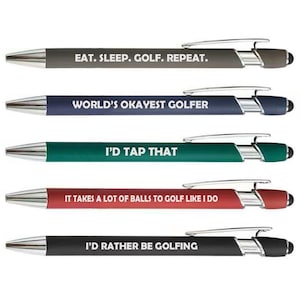 May include: Five ballpoint pens with silver accents and black touch tips. Each pen has a different color barrel and a golf-related phrase in white text: "EAT. SLEEP. GOLF. REPEAT.", "WORLD'S OKAYEST GOLFER", "I'D TAP THAT", "IT TAKES A LOT OF BALLS TO GOLF LIKE I DO", and "I'D RATHER BE GOLFING."