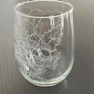 May include: A clear glass wine glass with an etched map of Sydney, Australia. The map includes major roads, highways, and landmarks like Chatswood, Marrickville, and Mascot.