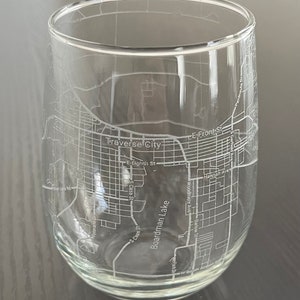 May include: Clear stemless wine glass etched with a map of Traverse City, Michigan. The map includes street names such as E Eighth St, S Cass St, and Boardman Lake. The glass is cylindrical with a rounded bottom.