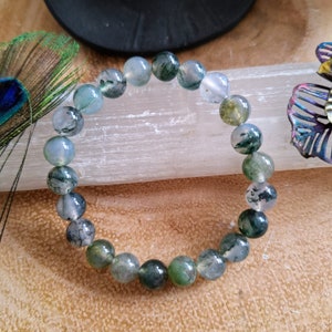 May include: A green and white agate gemstone bracelet with round beads. The bracelet is made of natural stones and has a polished finish.
