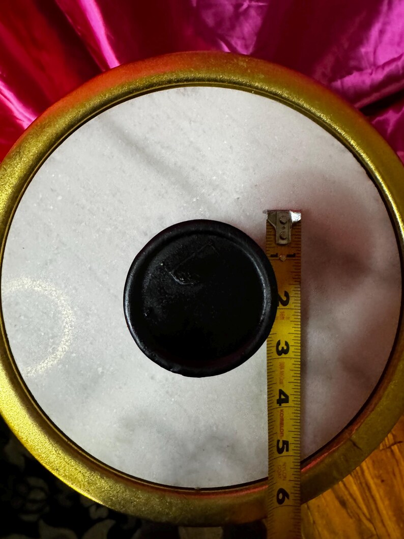 K&ouml;nnte beinhalten: Ein rundes Objekt aus wei&szlig;em Marmor mit einem schwarzen Mittelteil und einem goldfarbenen Rand. Ein Ma&szlig;band zeigt einen Durchmesser von etwa 12,7 cm. Es k&ouml;nnte sich um ein dekoratives Element oder einen Deckel handeln.