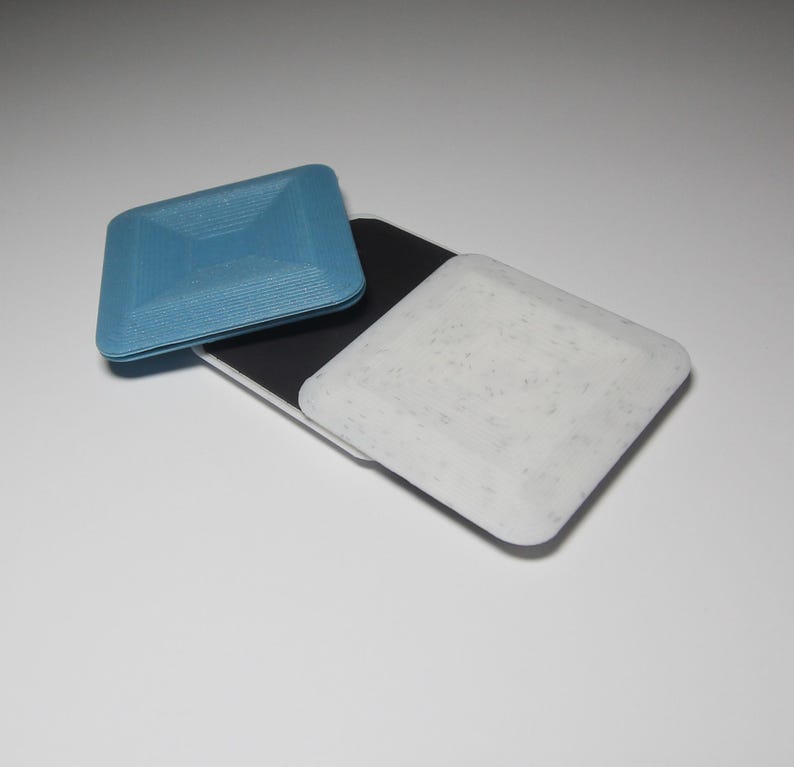 K&ouml;nnte beinhalten: Zwei quadratische Untersetzer, einer blau und einer wei&szlig; mit einem gesprenkelten Muster. Die Untersetzer sind aus einem strukturierten Material.