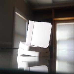 May include: A stack of three white rectangular blocks, each with a slightly different size and shape. The blocks are made of a smooth, hard material and have a clean, modern look.
