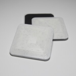 K&ouml;nnte beinhalten: Drei quadratische RFID-Tags, einer schwarz und zwei wei&szlig;. Die wei&szlig;en Tags haben ein konzentrisches Kreis-Muster.