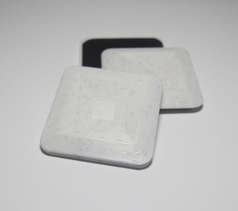 K&ouml;nnte beinhalten: Drei quadratische RFID-Tags, einer schwarz und zwei wei&szlig;. Die wei&szlig;en Tags haben ein konzentrisches Kreis-Muster.