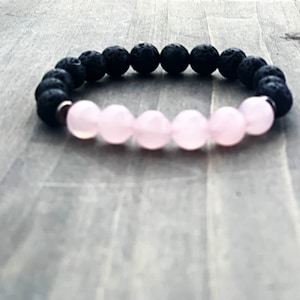 May include: A black lava rock and rose quartz beaded bracelet. The bracelet is made with small, round beads.