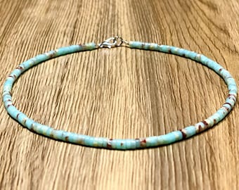 May include: A delicate blue and brown beaded necklace with a silver clasp.