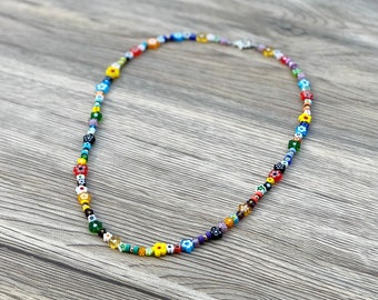 May include: A colourful beaded necklace with small flower-shaped beads in various colours, including red, yellow, blue, green, and white.