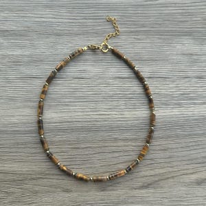 May include: A gold chain necklace with brown tiger's eye beads.