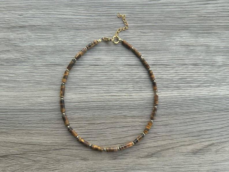 May include: A gold chain necklace with brown tiger's eye beads.