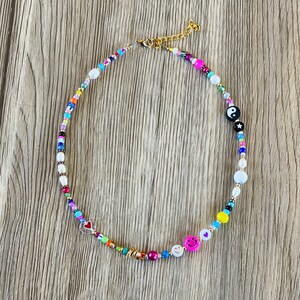 Op de afbeelding: Een kleurrijke kralenketting met verschillende bedels, waaronder een hart, een smiley en een yin yang symbool.