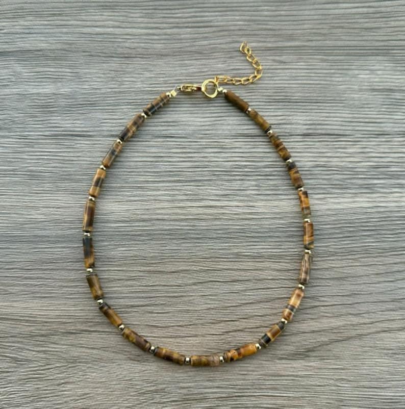 May include: A gold chain necklace with brown and gold tiger's eye beads.