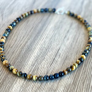 May include: A blue and gold tiger's eye beaded necklace with a silver clasp.