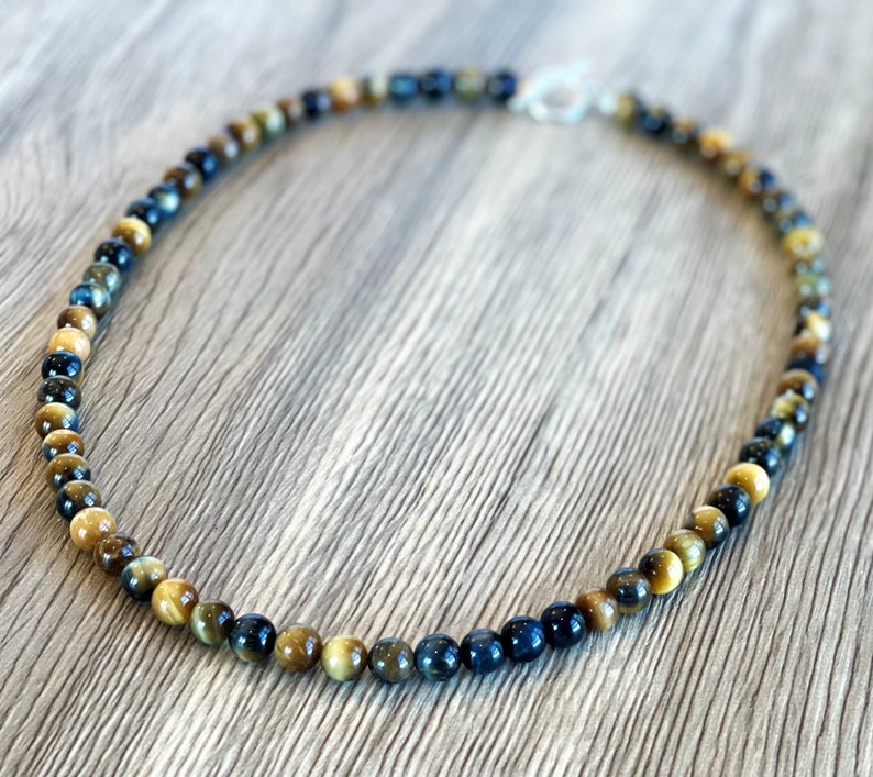 May include: A blue and gold tiger's eye beaded necklace with a silver clasp.