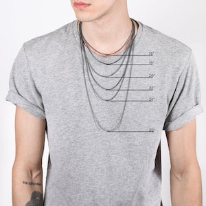 May include: A person wearing a gray t-shirt with several silver chain necklaces of varying lengths. The necklaces are displayed at 16, 18, 20, 22, 24, and 30 inches. The image is against a white background.