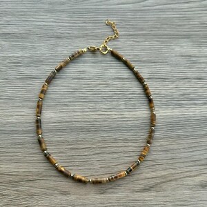 May include: A gold chain necklace with brown and gold tiger's eye beads.