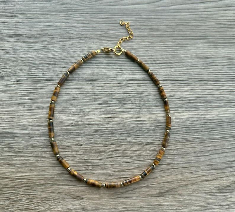 May include: A gold chain necklace with brown and gold tiger's eye beads.