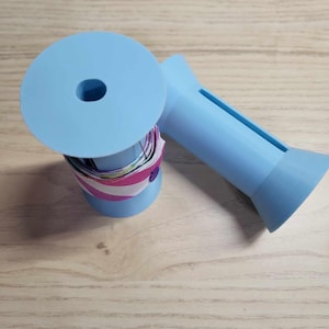 May include: Two light blue plastic spool holders for ribbon or yarn. One spool holder has a colorful ribbon wound around it.