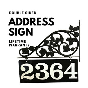 May include: Black metal double-sided address sign with a floral design. The sign has a black background with white numbers "2364".