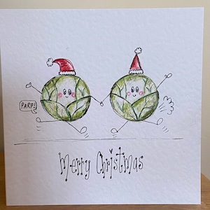 May include: A white Christmas card featuring two cartoon Brussels sprouts wearing Santa hats and holding hands. One sprout has a speech bubble that says "PARP!". The words "Merry Christmas" are written below the sprouts.
