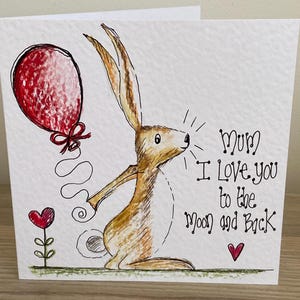 May include: A greeting card with a hand-drawn illustration of a brown hare holding a red balloon. The text reads "Mum I Love you to the moon and Back" with a red heart and flower.