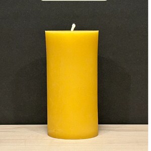 May include: A large, yellow beeswax candle with a white wick. The candle is 6 inches tall and has a burn time of 100 hours.