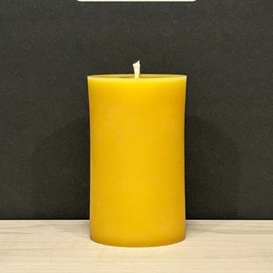 May include: A large, yellow, cylindrical candle with a single wick. The candle is 5 inches tall and has a burn time of 80 hours.
