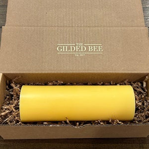 May include: A yellow candle in a cardboard box with the text "The Gilded Bee Est. 2017" on the lid.