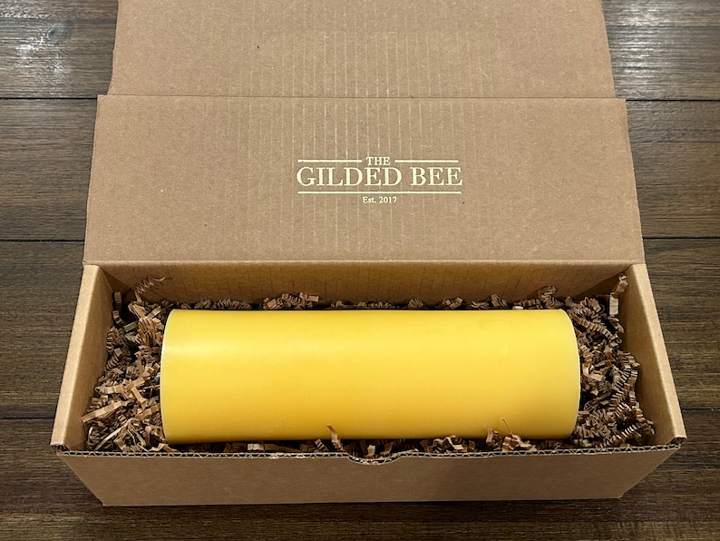 May include: A yellow candle in a cardboard box with the text "The Gilded Bee Est. 2017" on the lid.