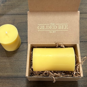 May include: A yellow beeswax candle in a cardboard box with the text "The Gilded Bee Est. 2017" on the lid.