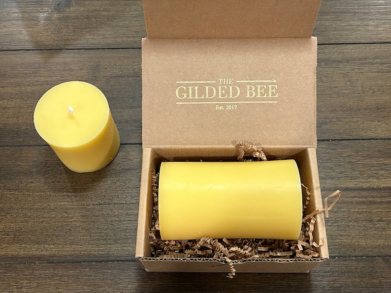 May include: A yellow beeswax candle in a cardboard box with the text "The Gilded Bee Est. 2017" on the lid.