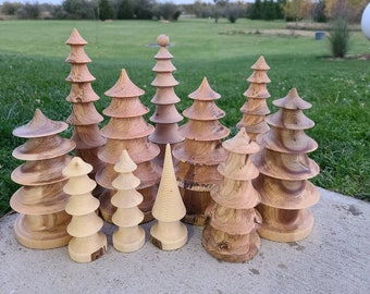 Op de afbeelding: Een verzameling van 10 houten kerstboomversieringen in verschillende maten en tinten bruin en beige. De versieringen zijn in een gelaagde vorm gestapeld, wat een unieke en feestelijke uitstraling creëert.