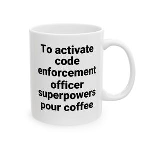 May include: A white ceramic mug with a handle featuring black text that reads: To activate code enforcement officer superpowers pour coffee. The mug has a cylindrical shape and a smooth finish, designed for holding hot or cold beverages.