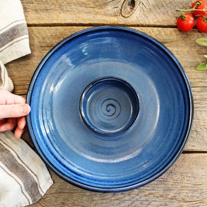 May include: A blue ceramic serving dish with a smaller bowl in the center. The dish has a dark blue rim and a slightly textured surface.
