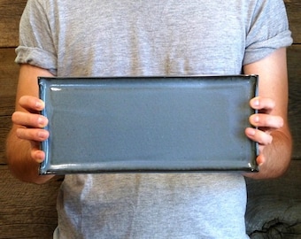 May include: A rectangular serving tray with a dark blue glaze and a black rim.
